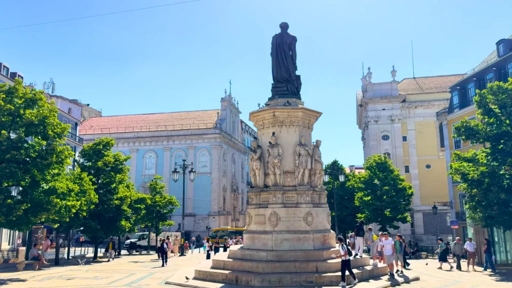 Monument to Luís de Camões in a sunny square in Lisbon, Portugal, with historic buildings and trees behind it Cheapest Country to Live in Europe: Camões Monument in Lisbon